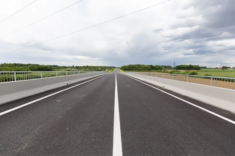 Newly constructed highway bridge with clear sky and greenery on both sides